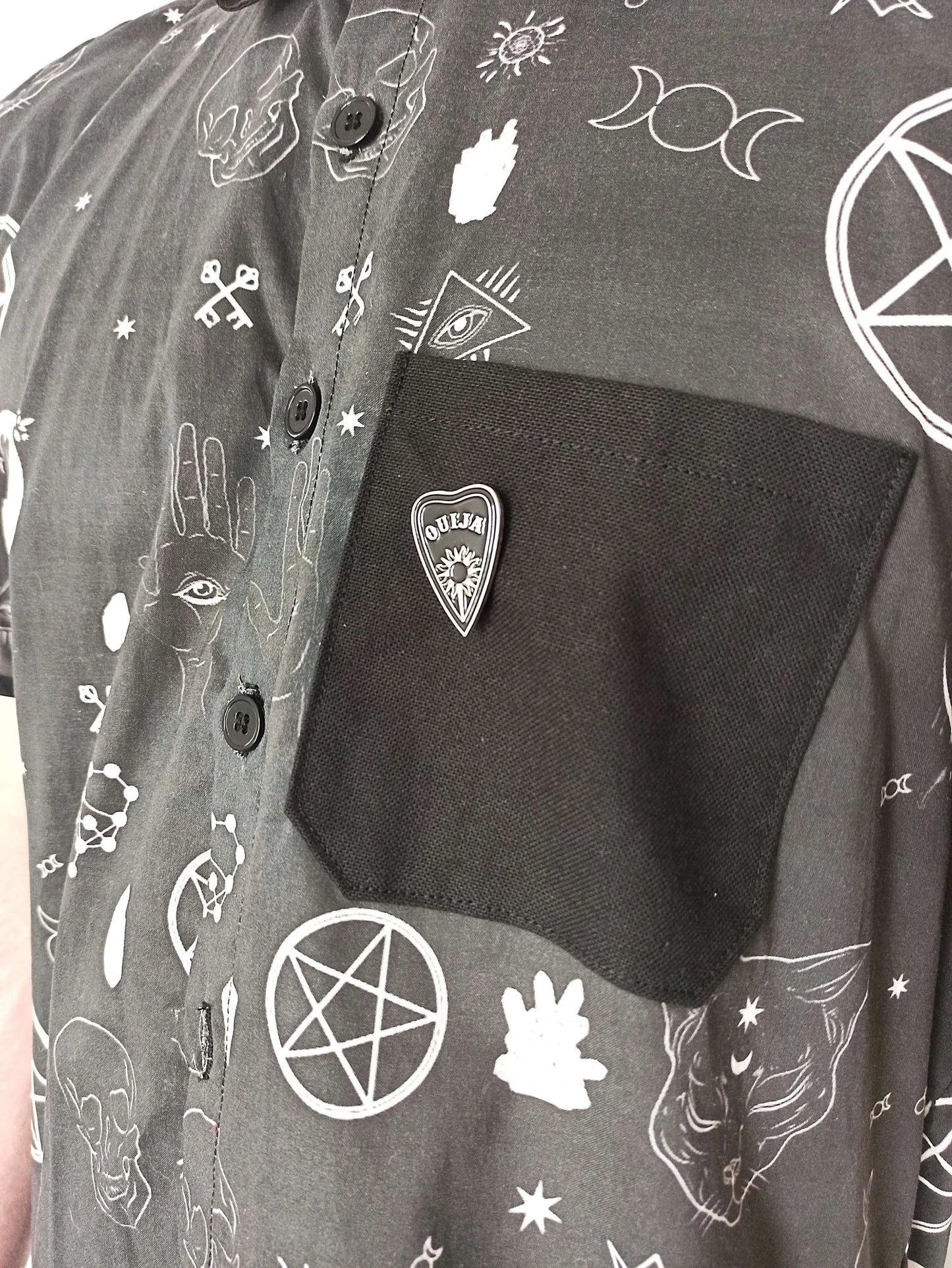 Détail de la poche avec pins ouija acier
Poche coton noir et détail ésotérique sur chemise
Détail boutons noirs acryliques sur chemise goth