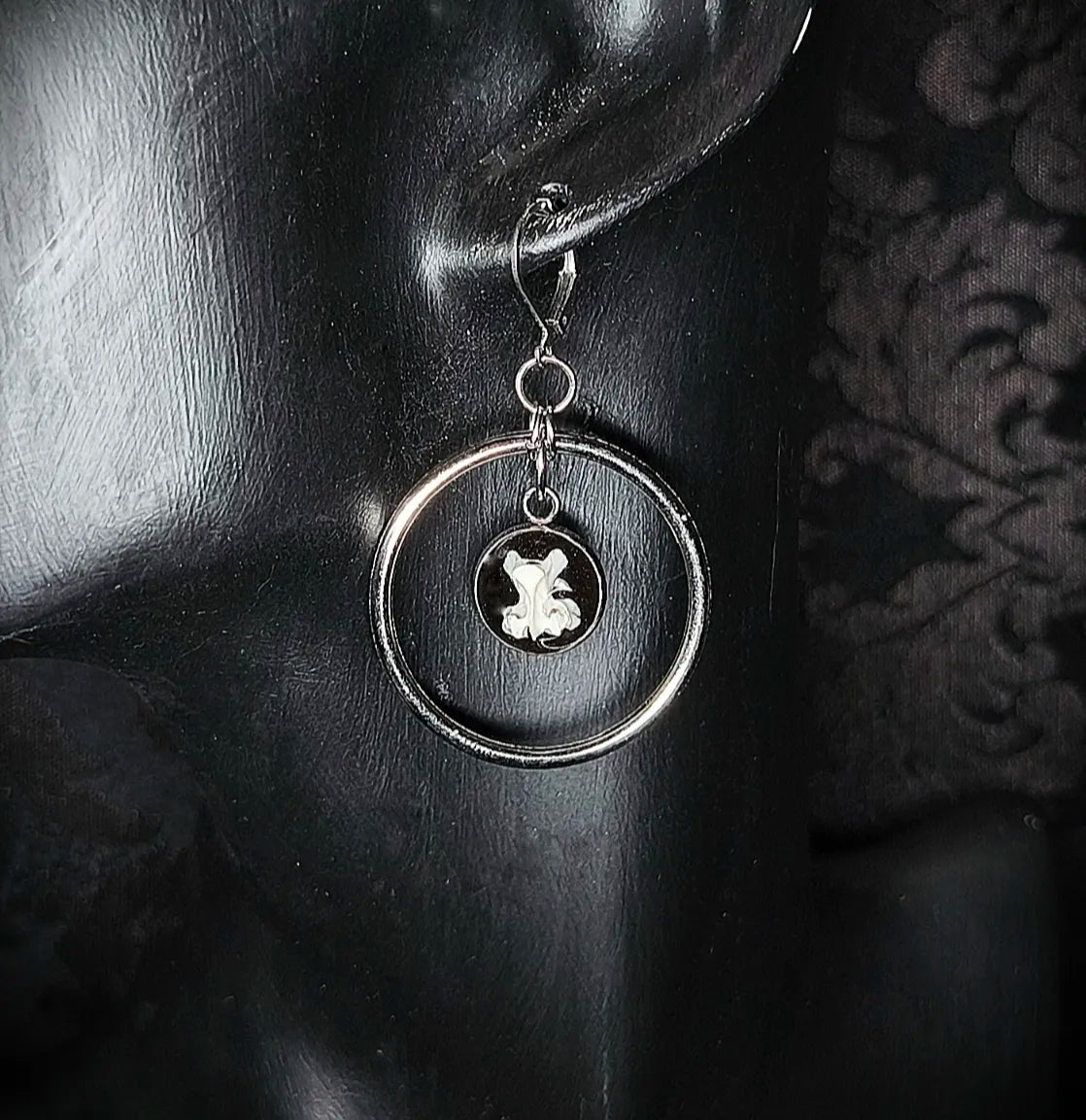 Détail du pendentif avec vertèbre de rongeur sur fond noir sous résine transparente et anneau en acier inoxydable fait main
