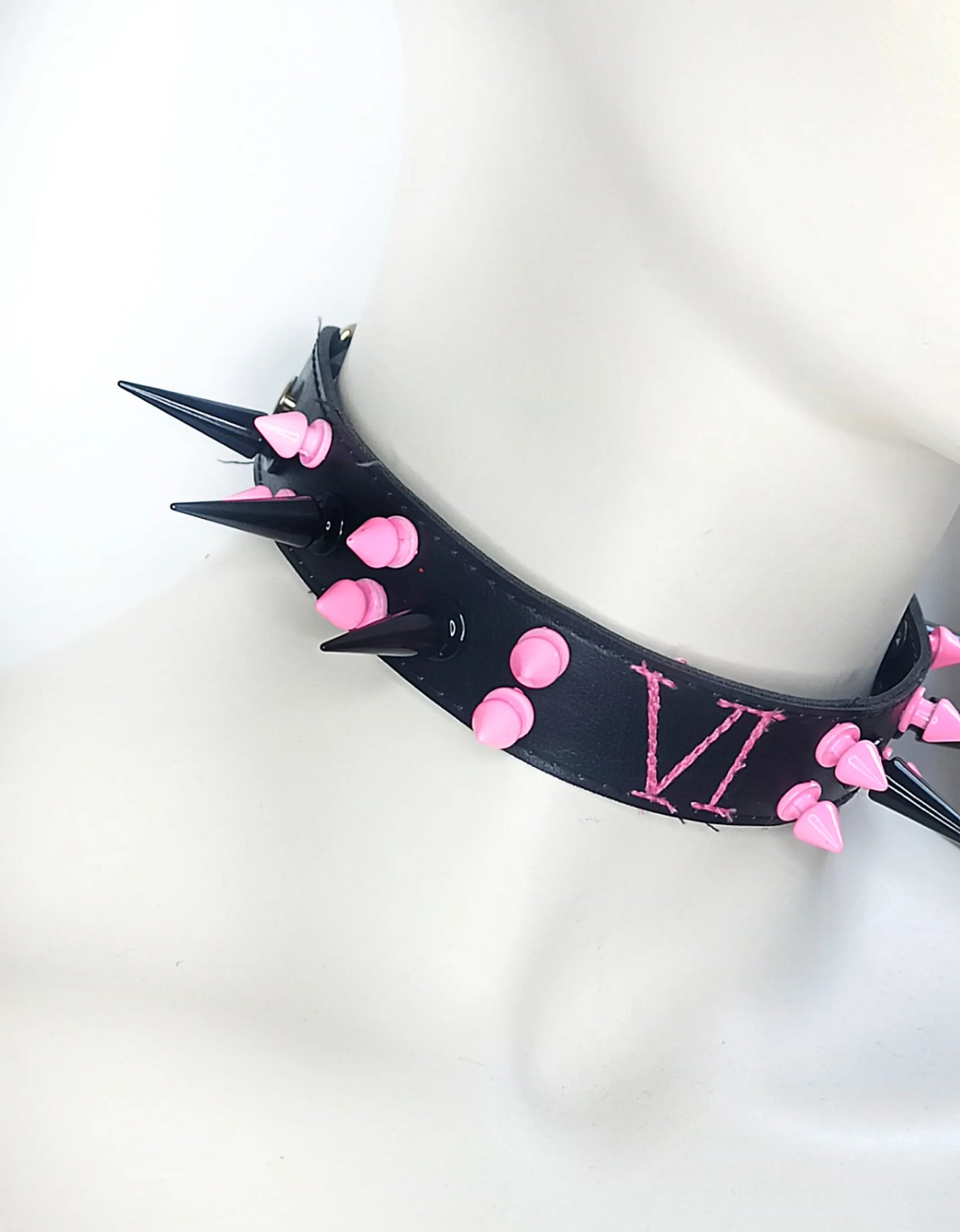 Détails des clous roses et noirs du choker de VI dans Arcane
Clous de différentes tailles noirs et roses