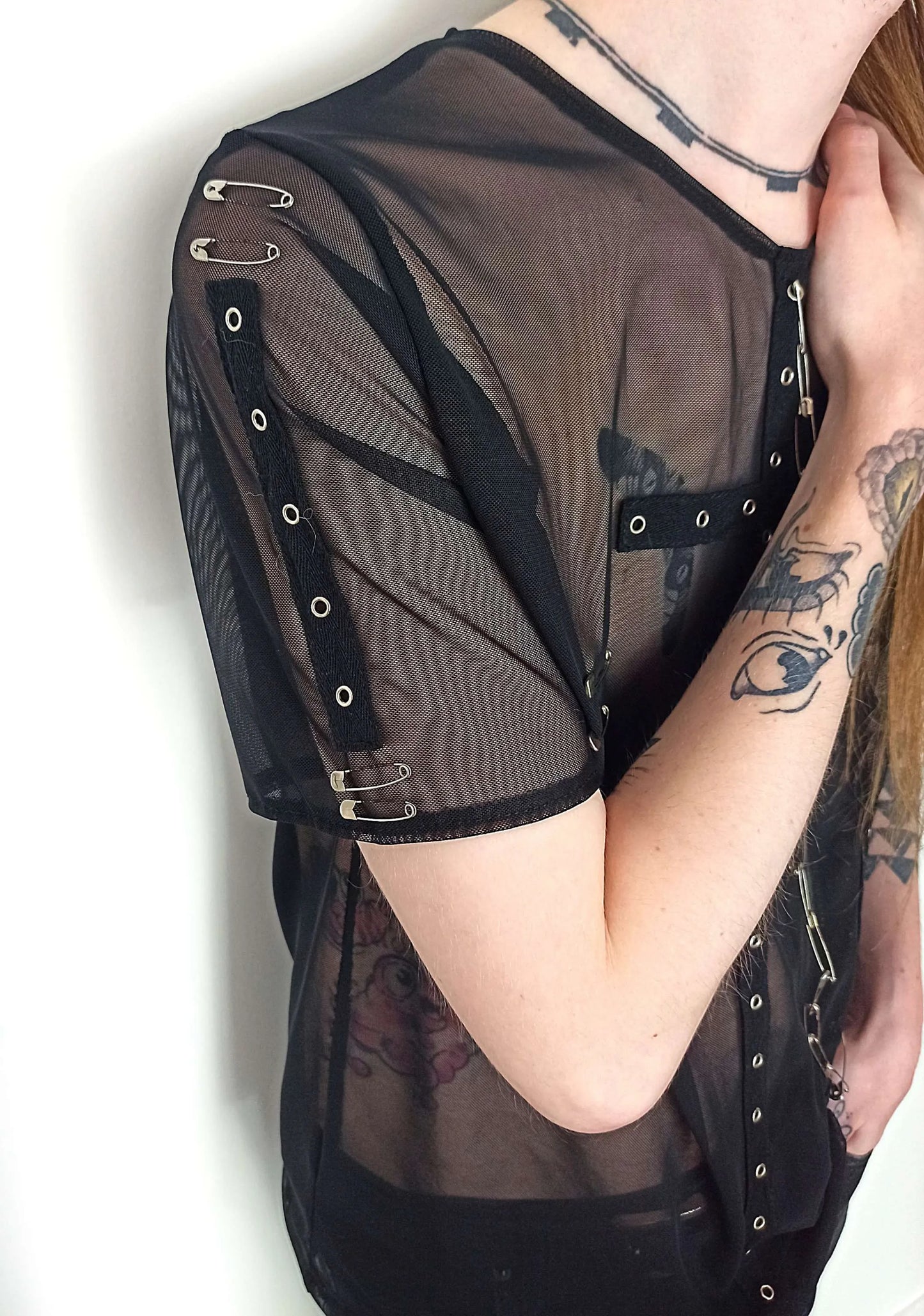 T-shirt dark transparent avec finitions en métal
Détails des manches avec bande d'oeillets et d'épingles à nourrice