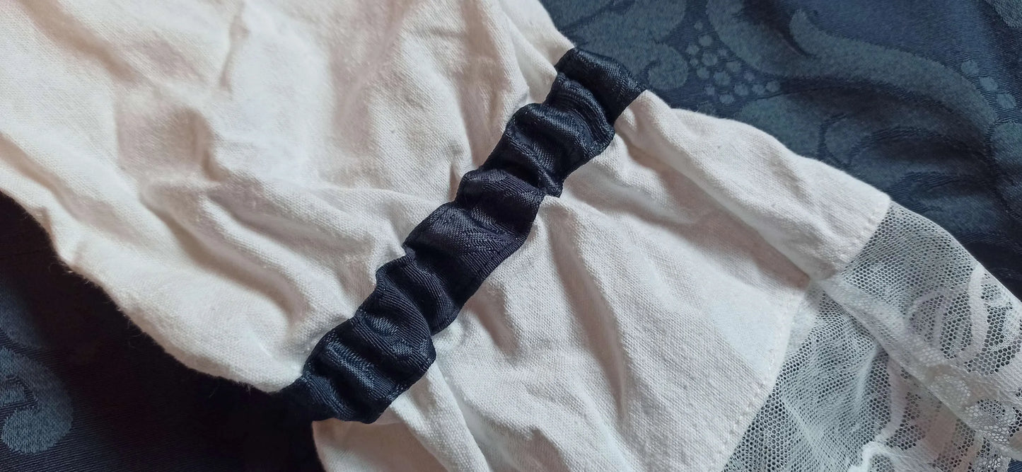 Texture jacquard bleu nuit avec arabesques gothiques
Détail des manches larges en lin et dentelle blanche