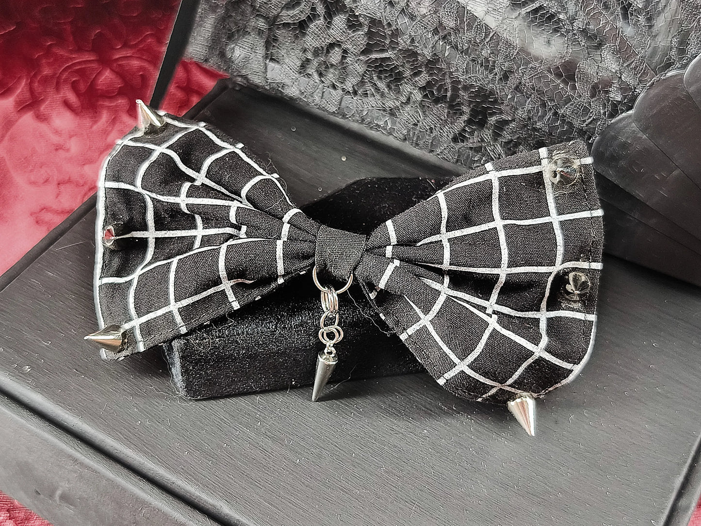 Barrette nœud noir à motif quadrillé décorée de clous argentés et d’un pendentif pointe