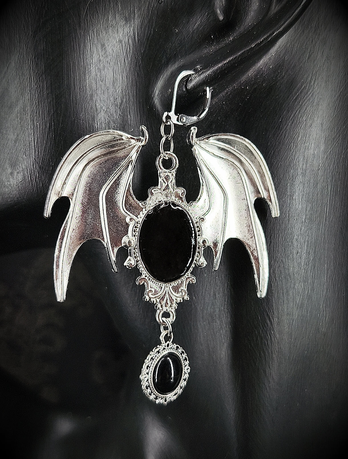 Boucle d’oreille gothique argentée à ailes de chauve-souris et cabochons noirs vue de près 