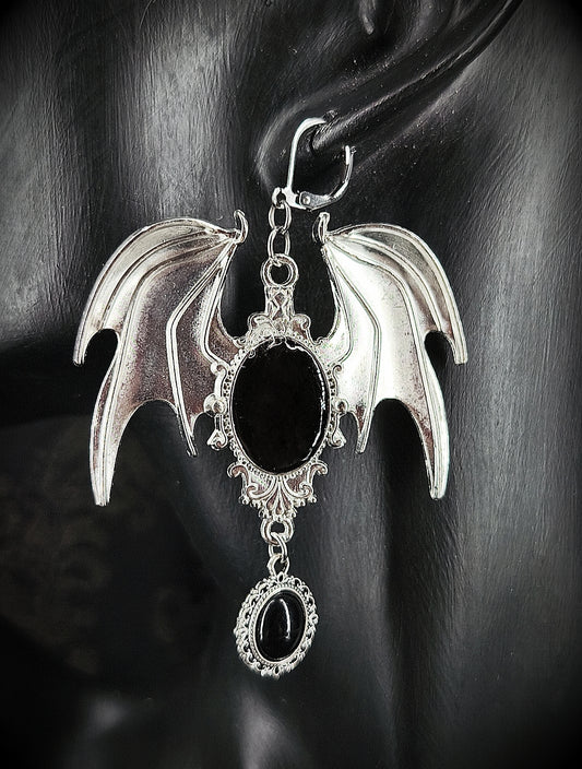 Boucle d’oreille gothique argentée à ailes de chauve-souris et cabochons noirs vue de près 