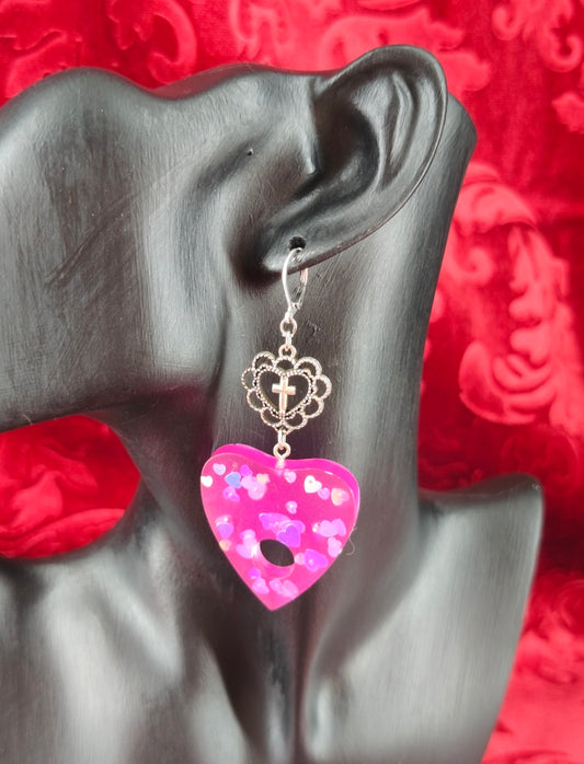 Boucles d’oreilles Ouija en résine magenta translucide avec cœurs holographiques et ornements gothiques portees