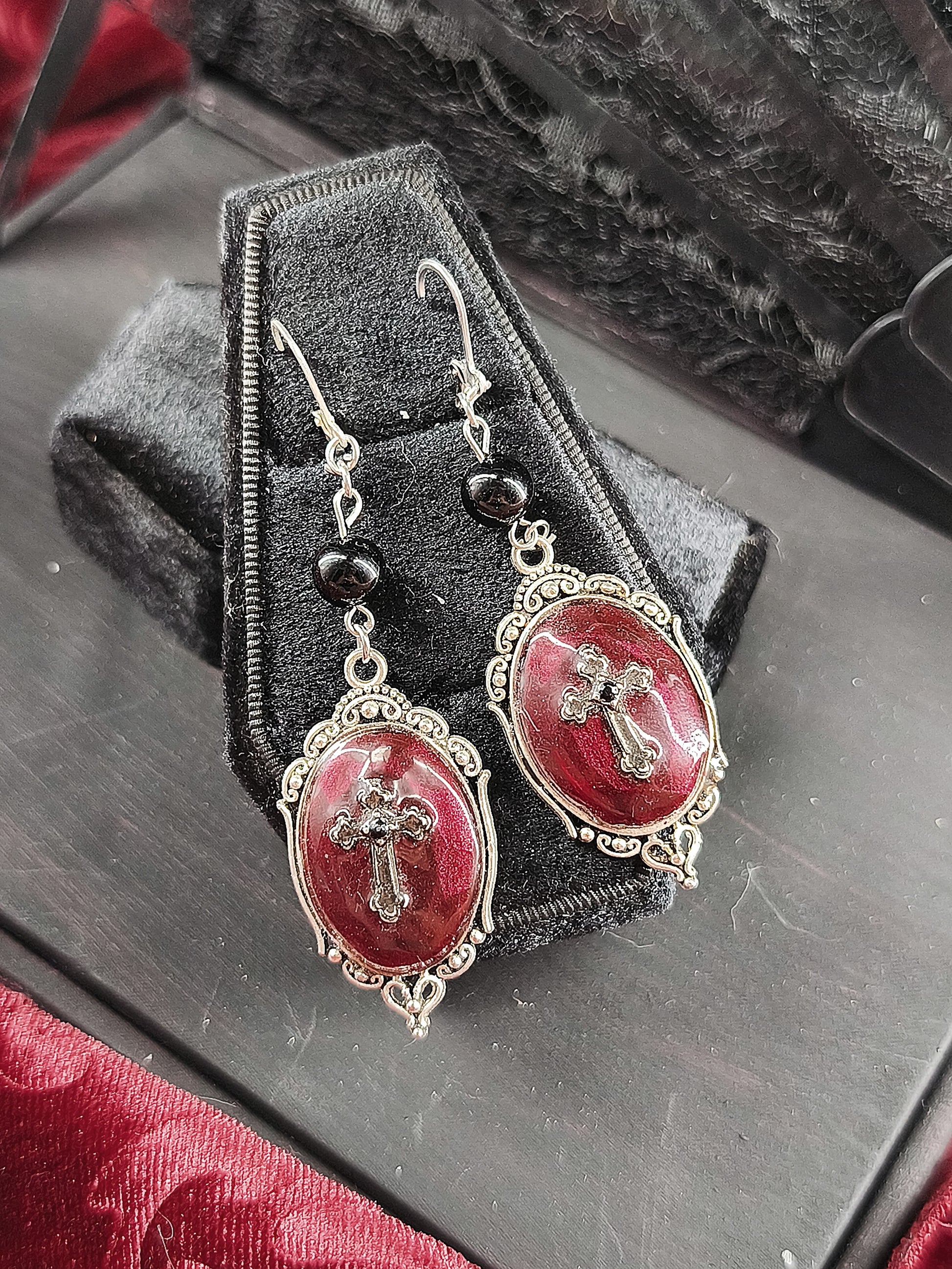 Boucles d’oreilles gothiques faites main avec médaillons rouges, croix argentées et perles noires.