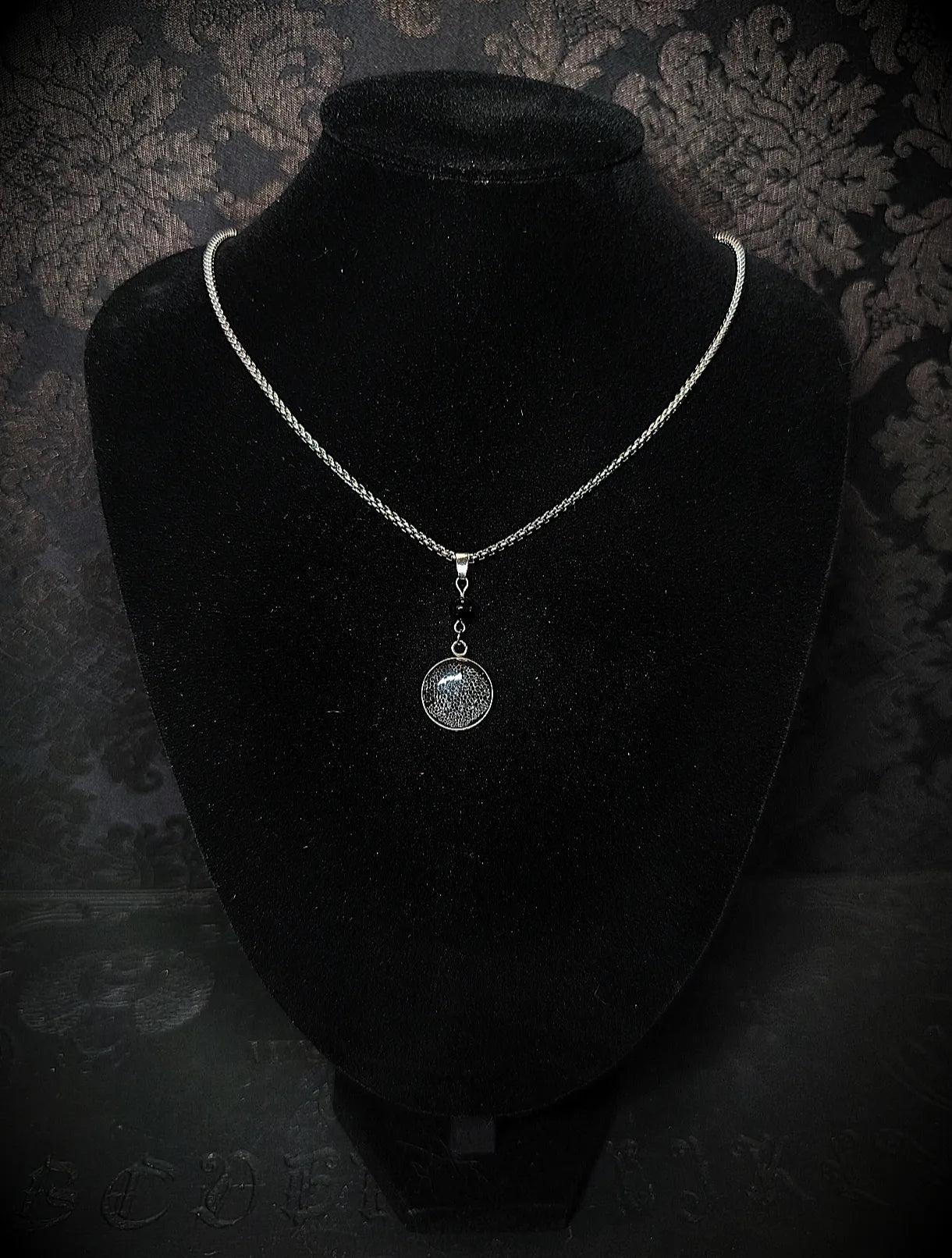 Collier naturaliste avec mue de gecko léopard incrustée dans résine UV sur fond noir