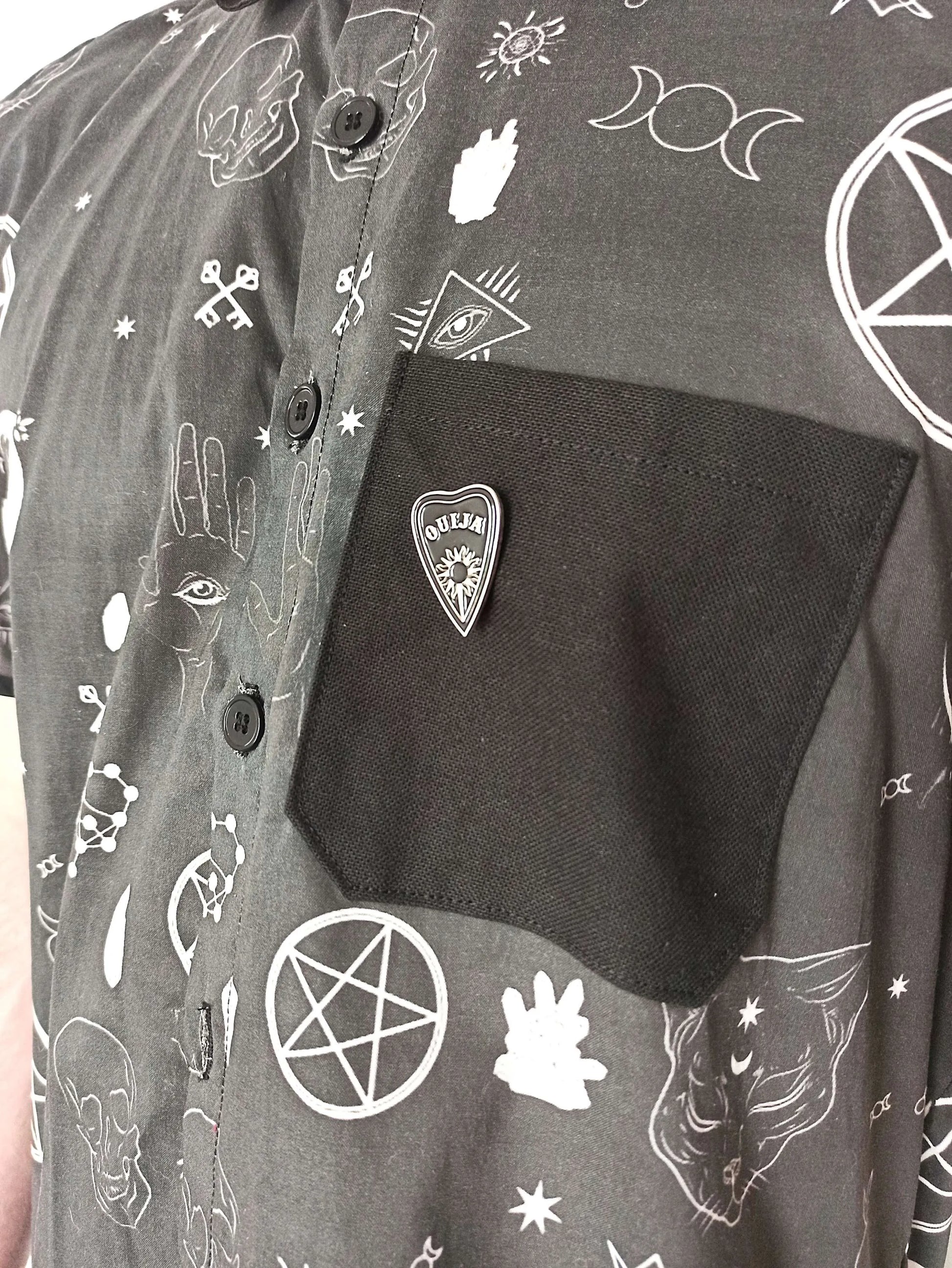 Détail de la poche avec pins ouija acier
Poche coton noir et détail ésotérique sur chemise
Détail boutons noirs acryliques sur chemise goth