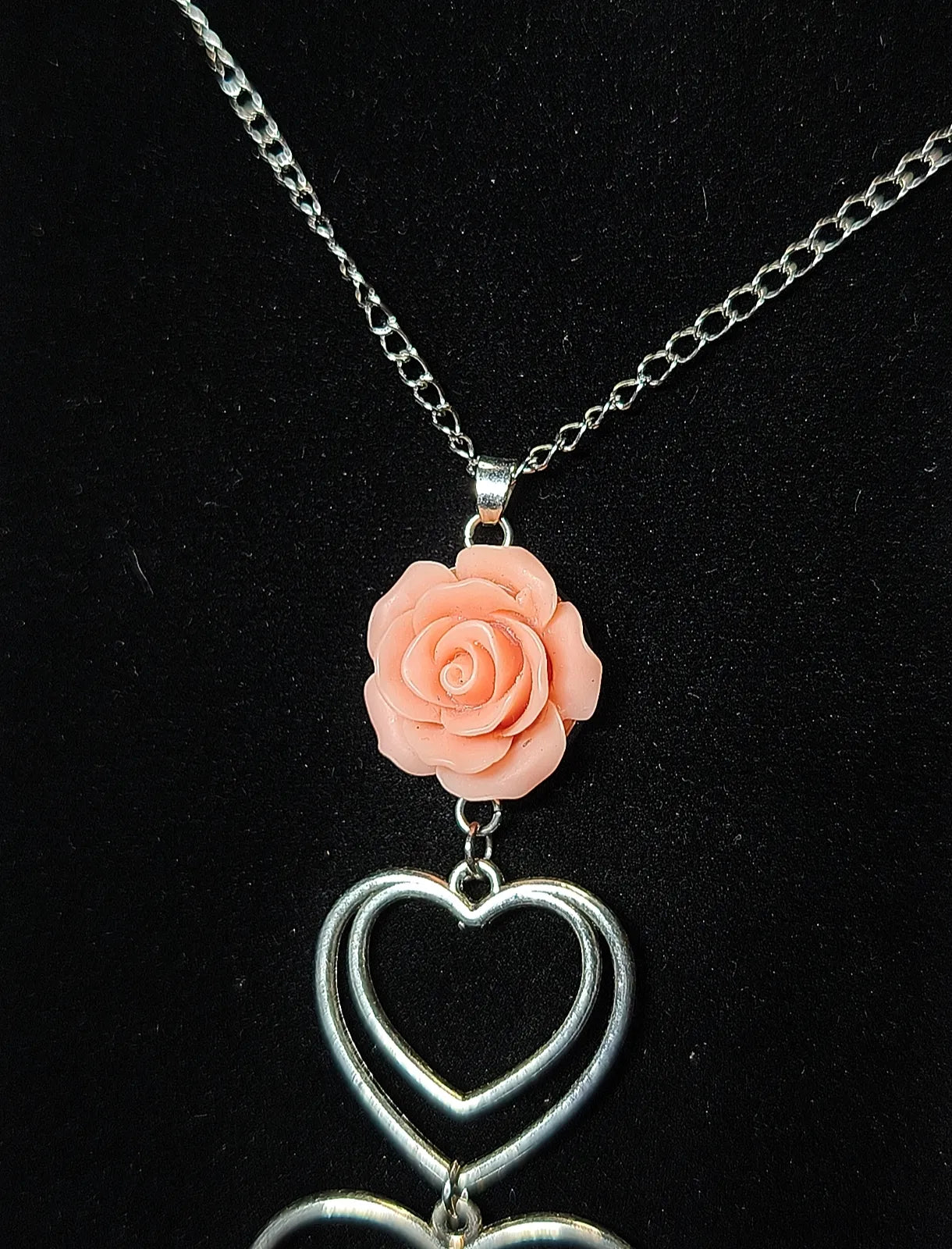 Détail de la rose vieux rose en résine époxy et du double cœur argenté du collier romantique gothique