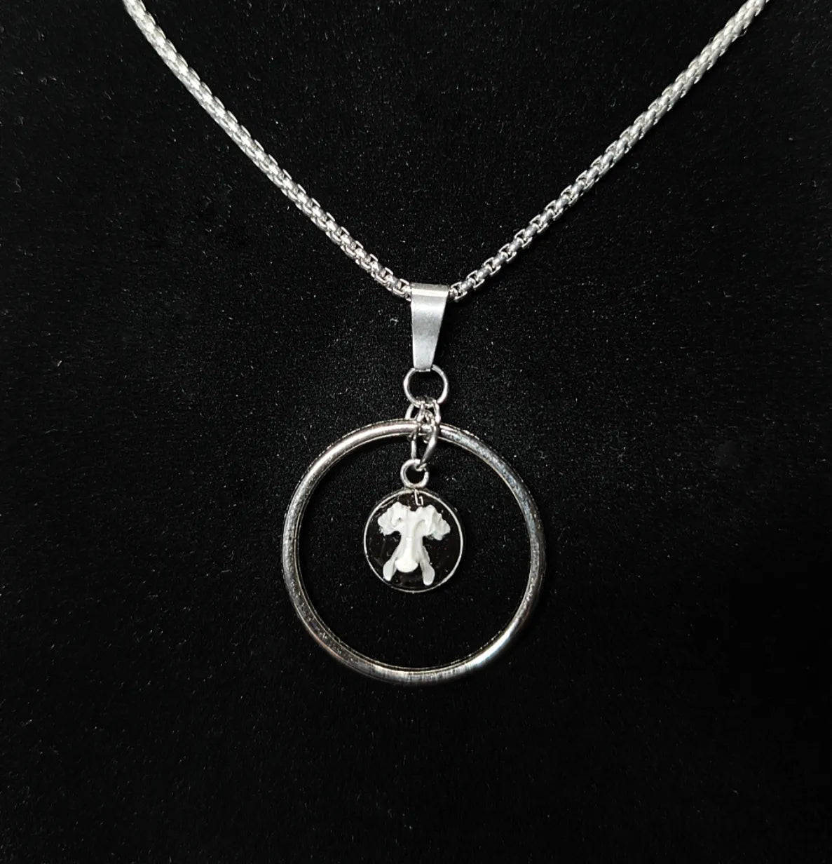 Détail du pendentif avec vertèbre de rongeur sur fond noir sous résine transparente et anneau en acier inoxydable