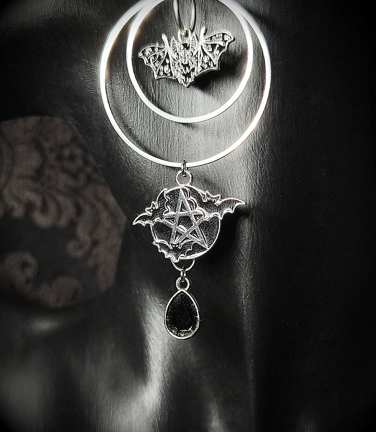 Détail du pendentif pentacle et chauves-souris avec perle en verre noir sur boucle d’oreille gothique