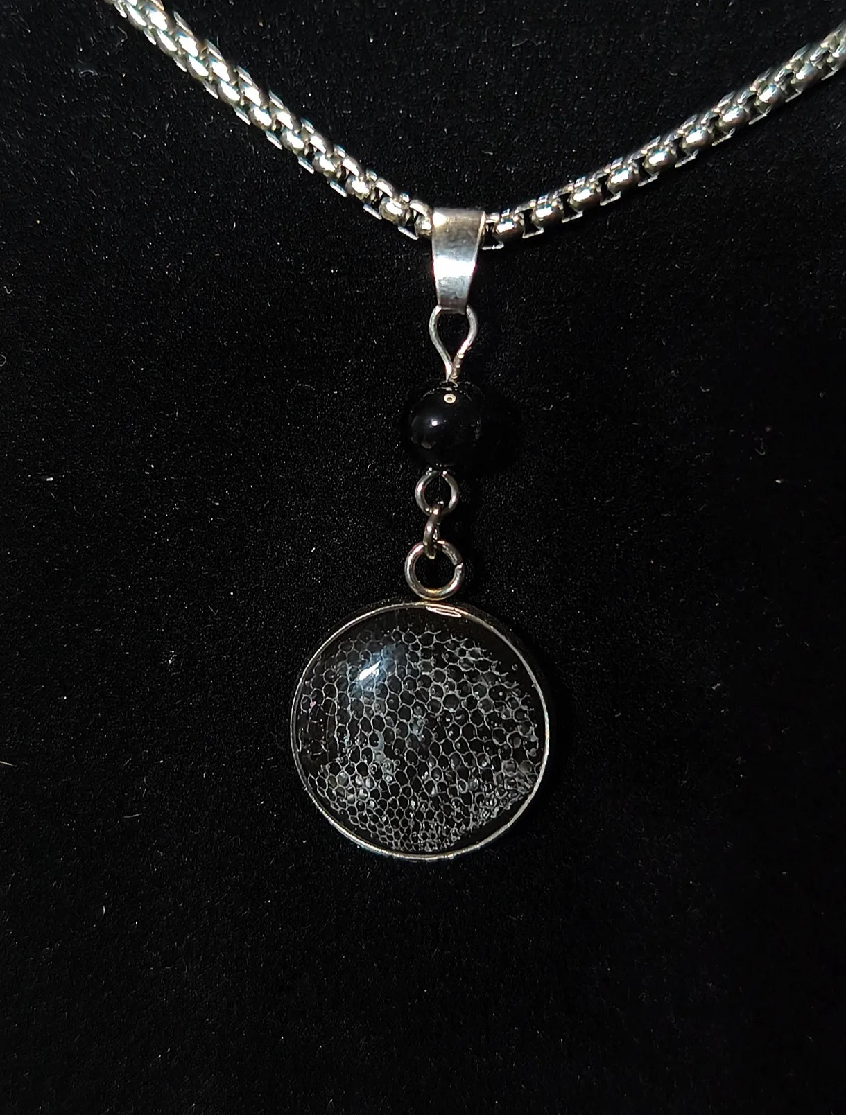 Détail pendentif en résine avec véritable mue de gecko léopard et perle noire 