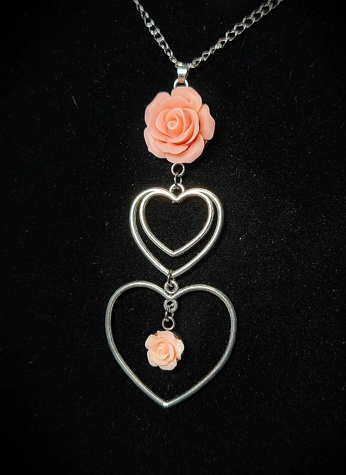 Gros plan du collier Cœur d’Antan avec roses en résine époxy vieux rose et pendentifs cœur argentés