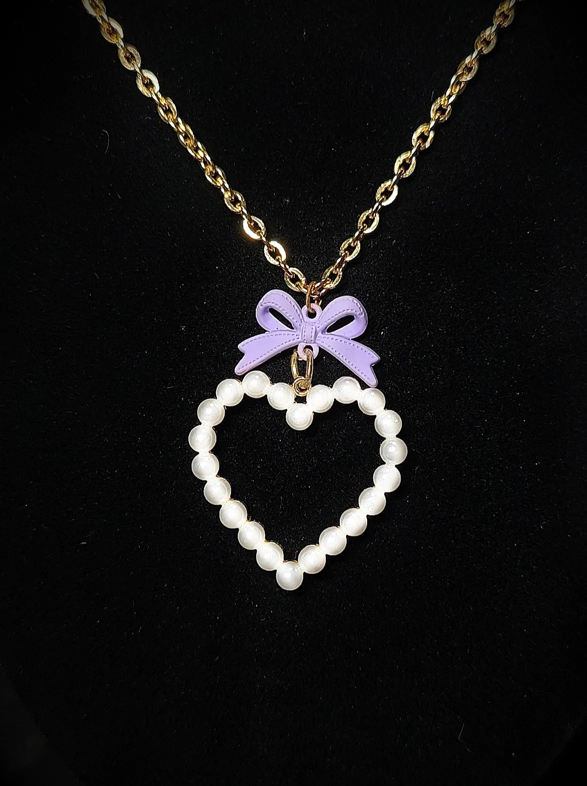 Gros plan du collier doré Cœur de Porcelaine avec cœur nacré et nœud violet pastel