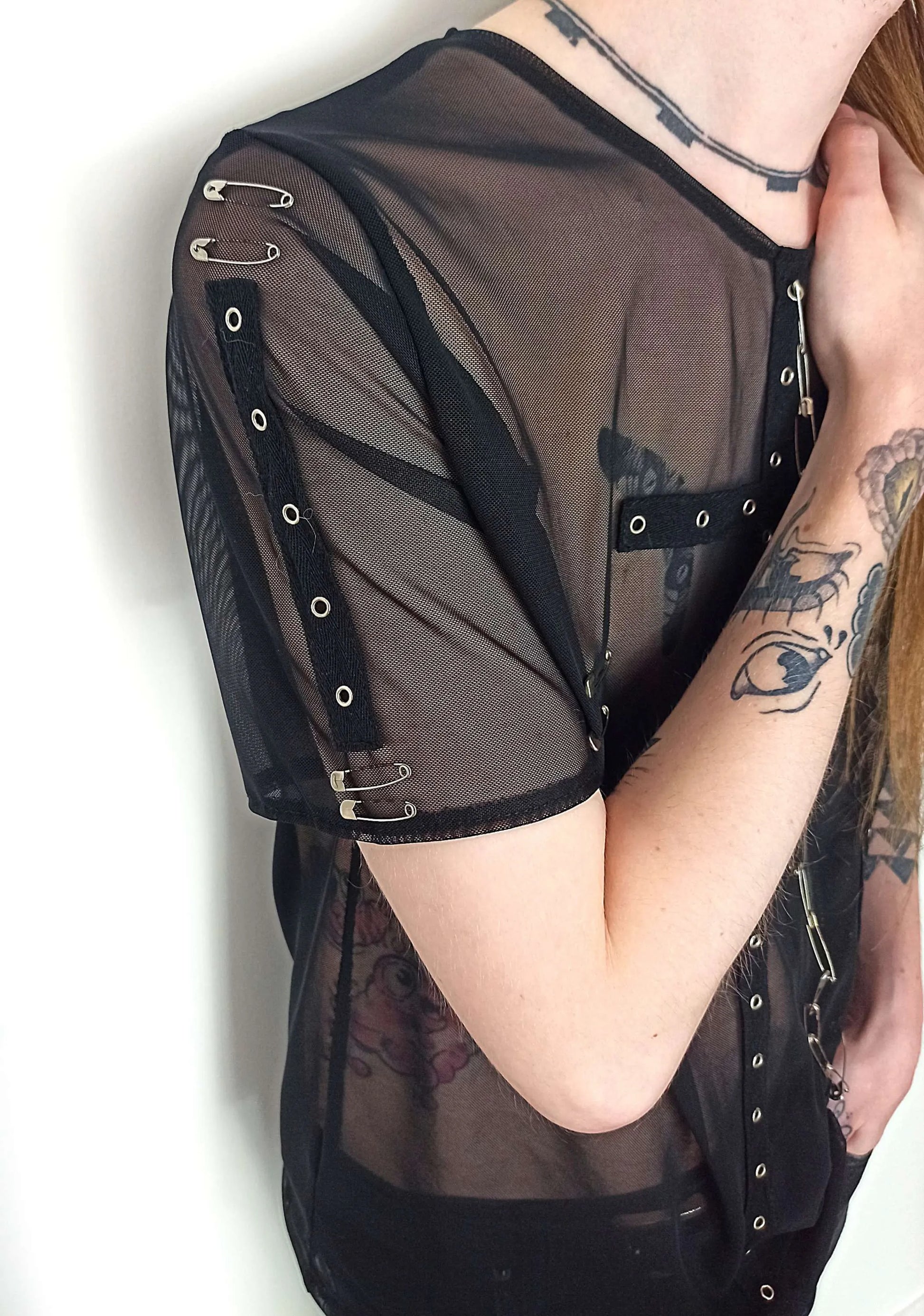 T-shirt dark transparent avec finitions en métal
Détails des manches avec bande d'oeillets et d'épingles à nourrice