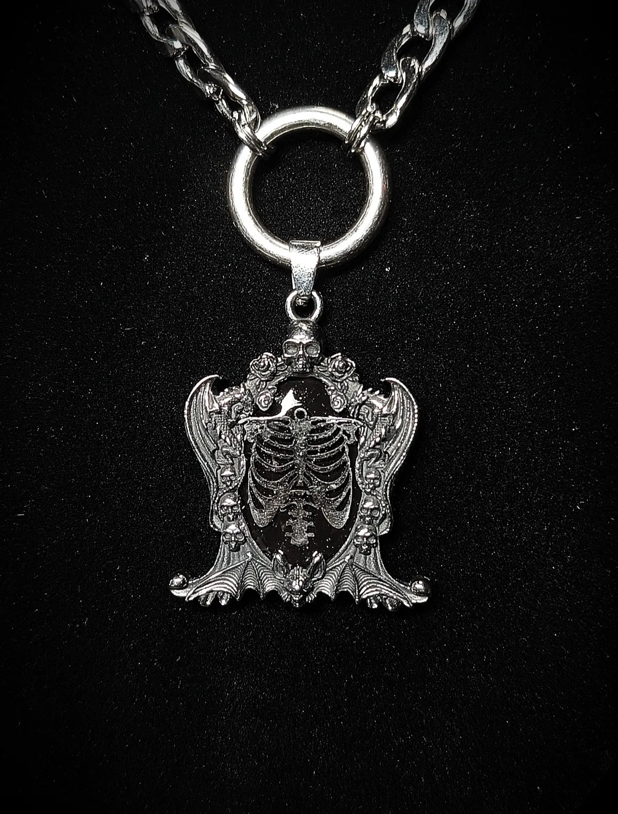 Pendentif gothique cage thoracique sur fond noir avec crânes et résine UV