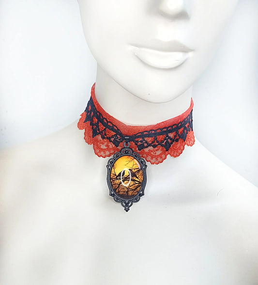 Ras de cou gothique en dentelle orange et noir avec corbeau fait main 
Vue de près du pendentif gothique corbeau orange