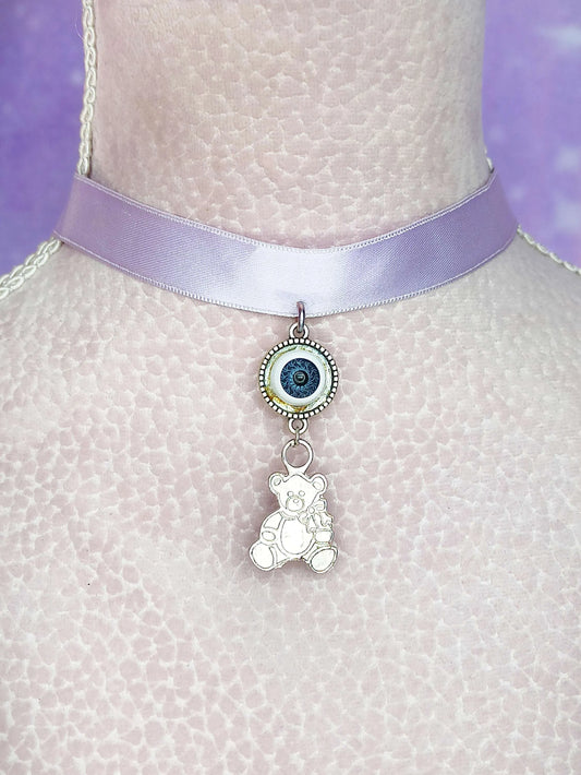 Ras de cou pastel goth violet avec pendentif ourson en métal et œil en verre, sur fond neutre