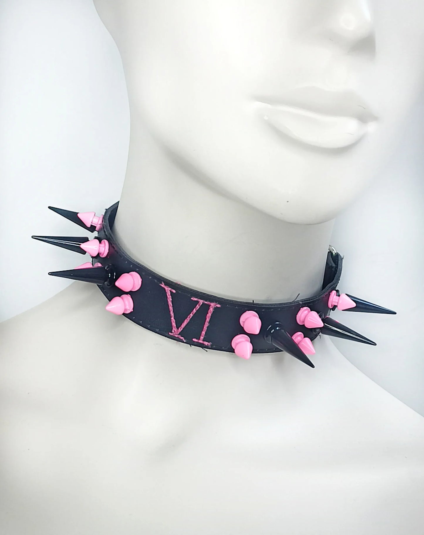 Tour de cou en cuir noir avec clous roses et noirs de Arcane 
Détails des clous 
