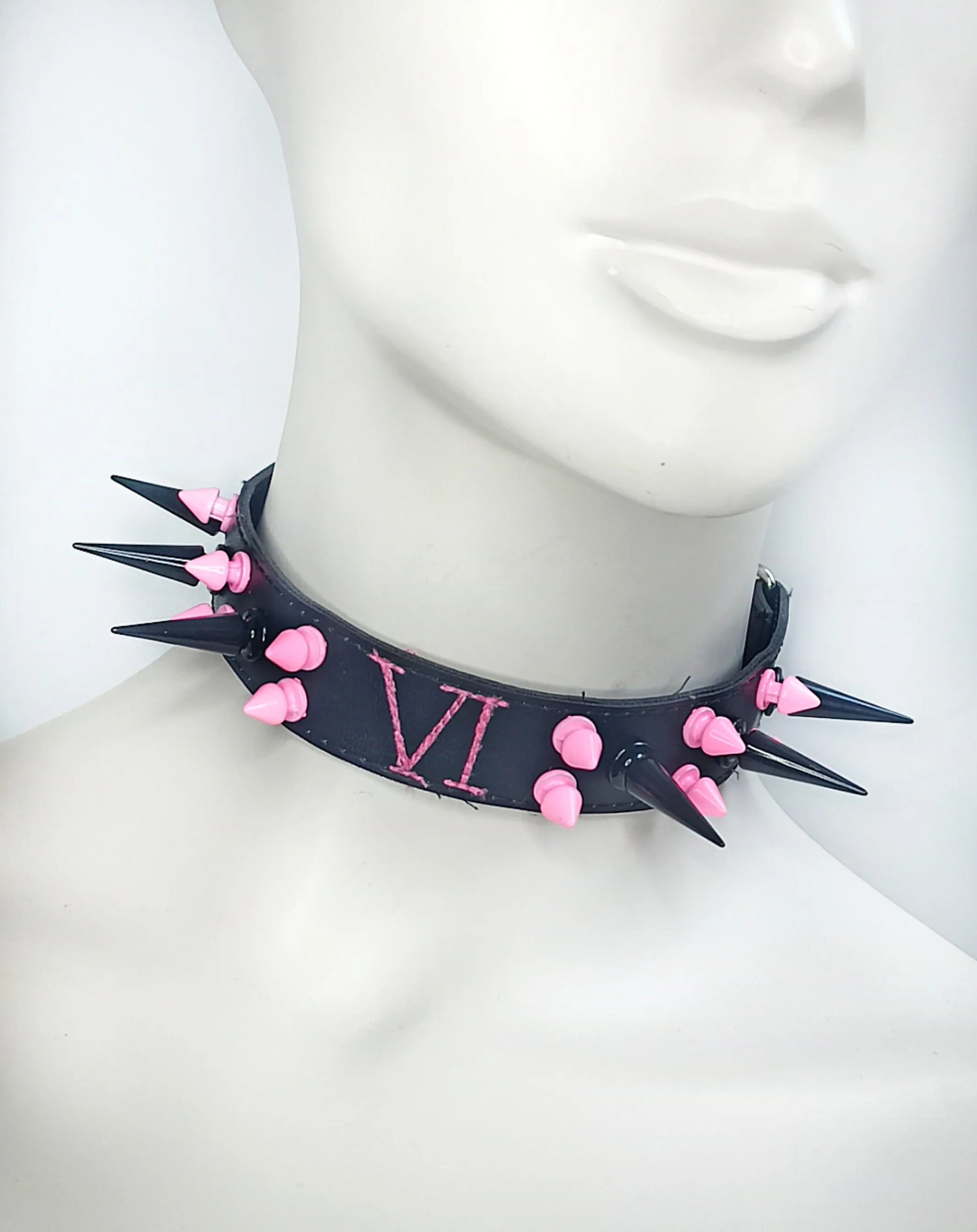 Tour de cou en cuir noir avec clous roses et noirs de Arcane 
Détails des clous 