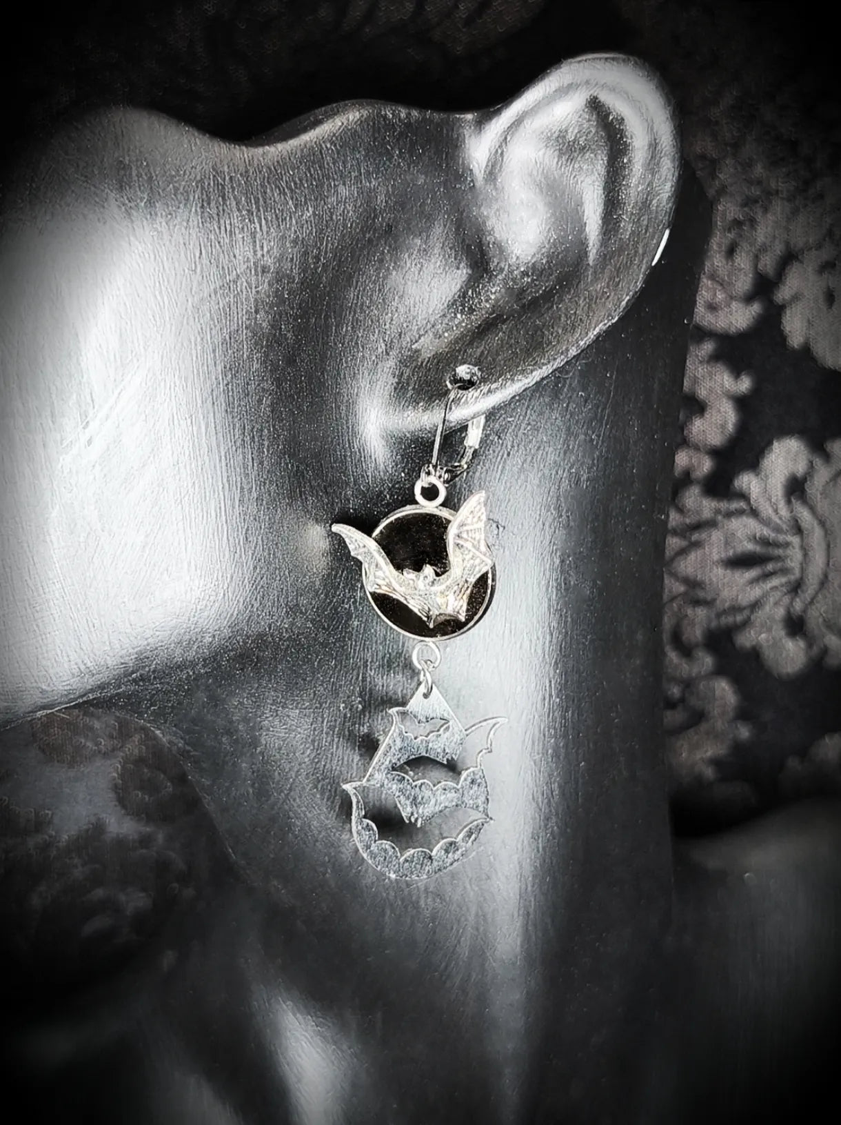 Vue rapprochée de boucle d’oreille chauve-souris argentée avec inclusion en résine UV noire